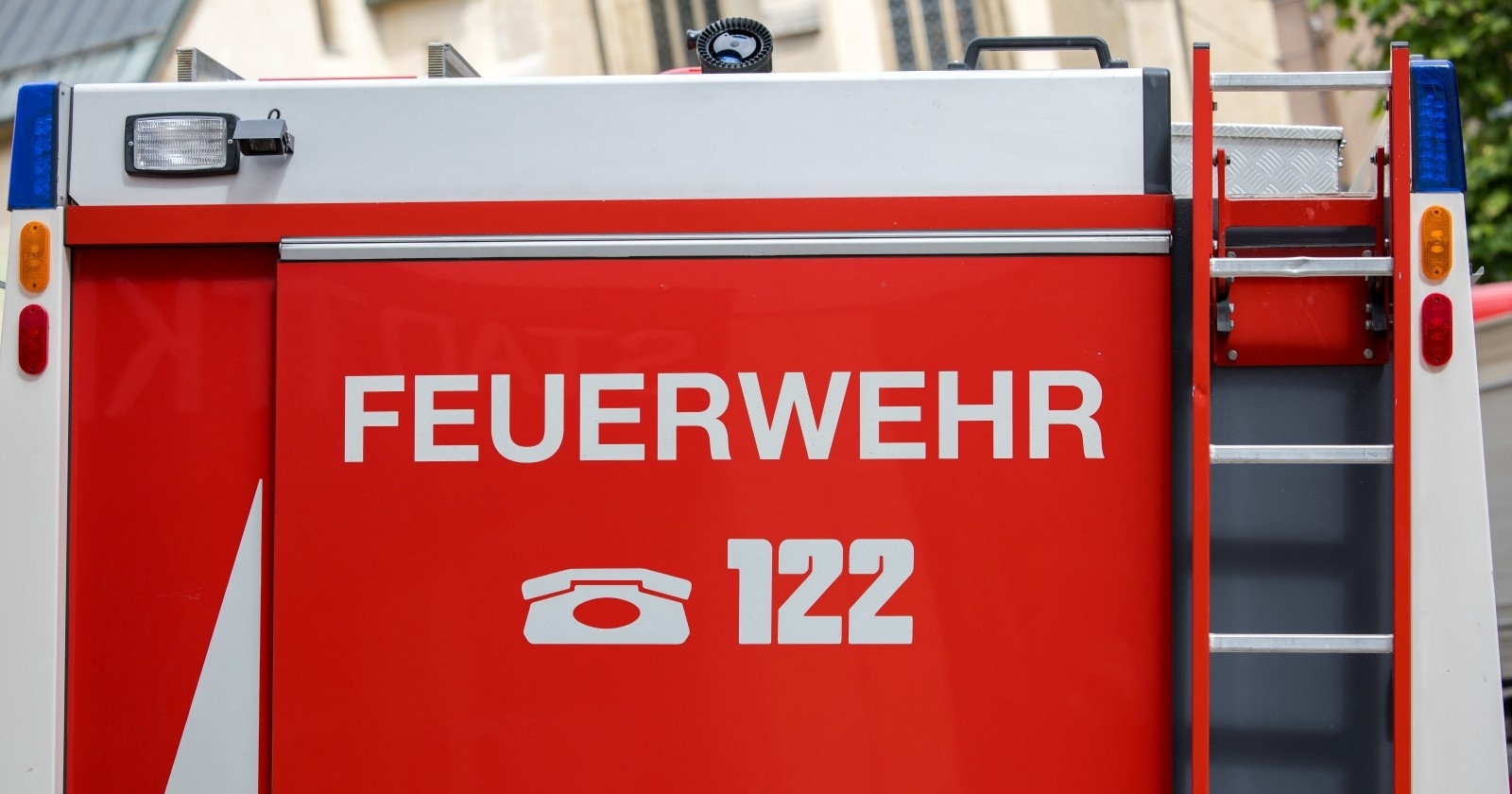 Feuerwehrauto mit deutschem Feuerwehrschild und Notrufnummer 122.