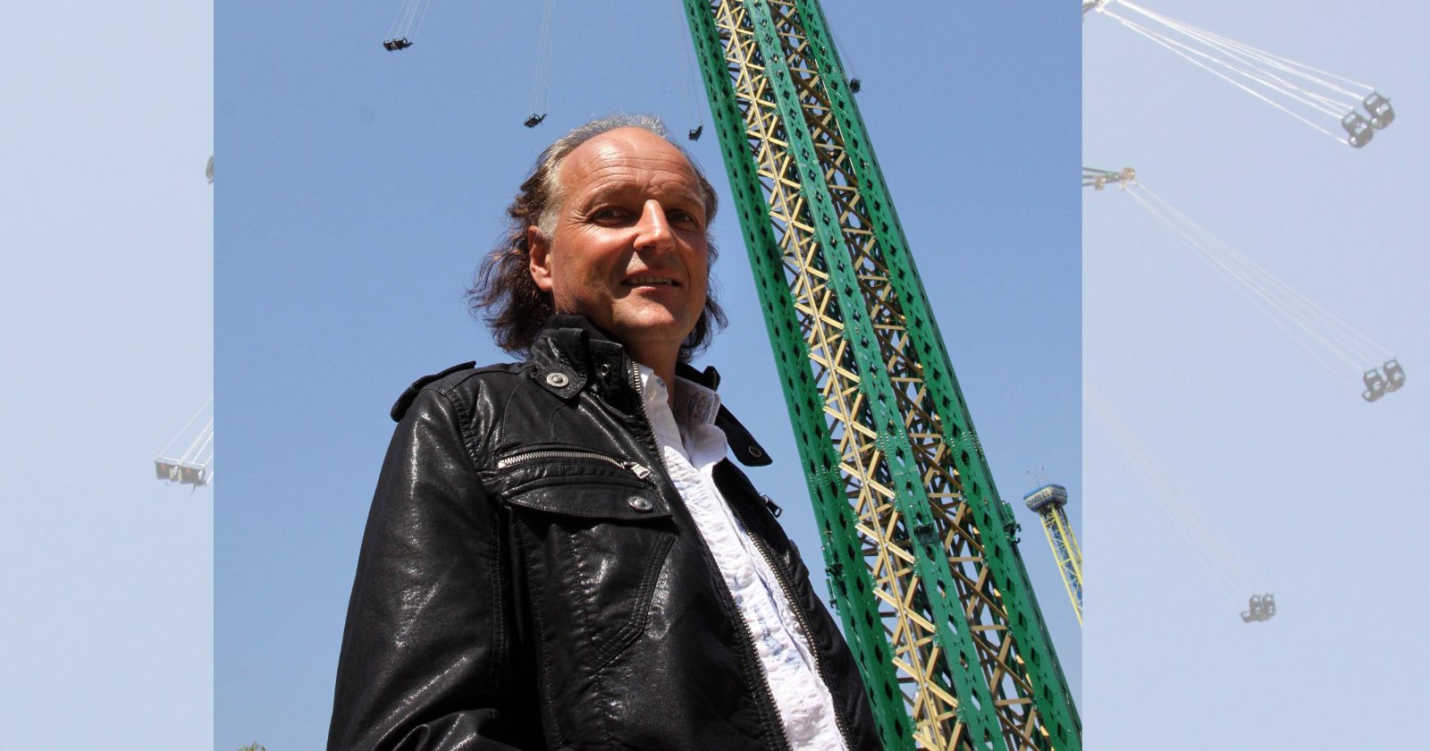Das berühmte, über 100 Meter hohe Kettenkarussell Prater Turm ragt in den blauen Himmel über dem Wiener Prater, Walter Pondorfer steht davor