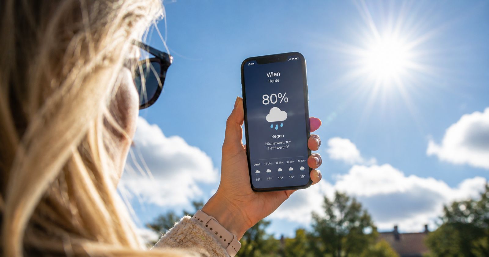 Frau schaut auf Smartphone mit Regenvorhersage bei strahlendem Sonnenschein und blauem Himmel