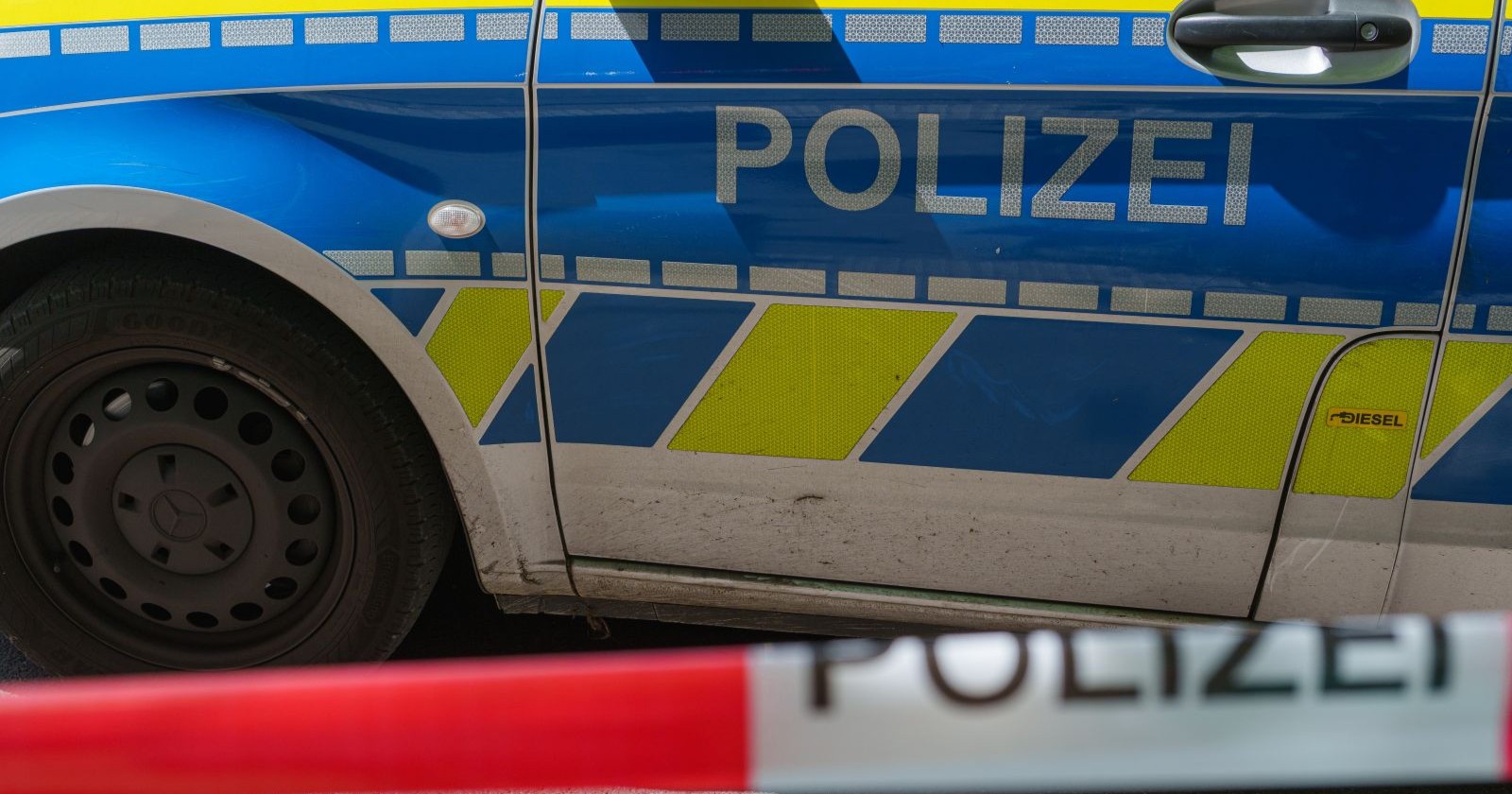 Polizeifahrzeug bei Einsatz nach Amoklauf an Schule in Bayern mit Absperrband im Vordergrund