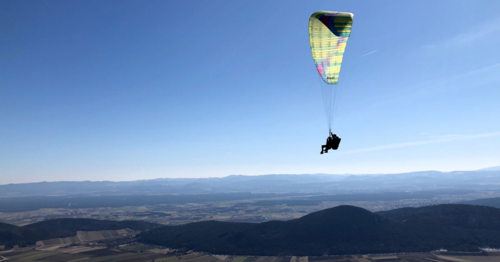 Paragleiter fliegt über eine Berglandschaft