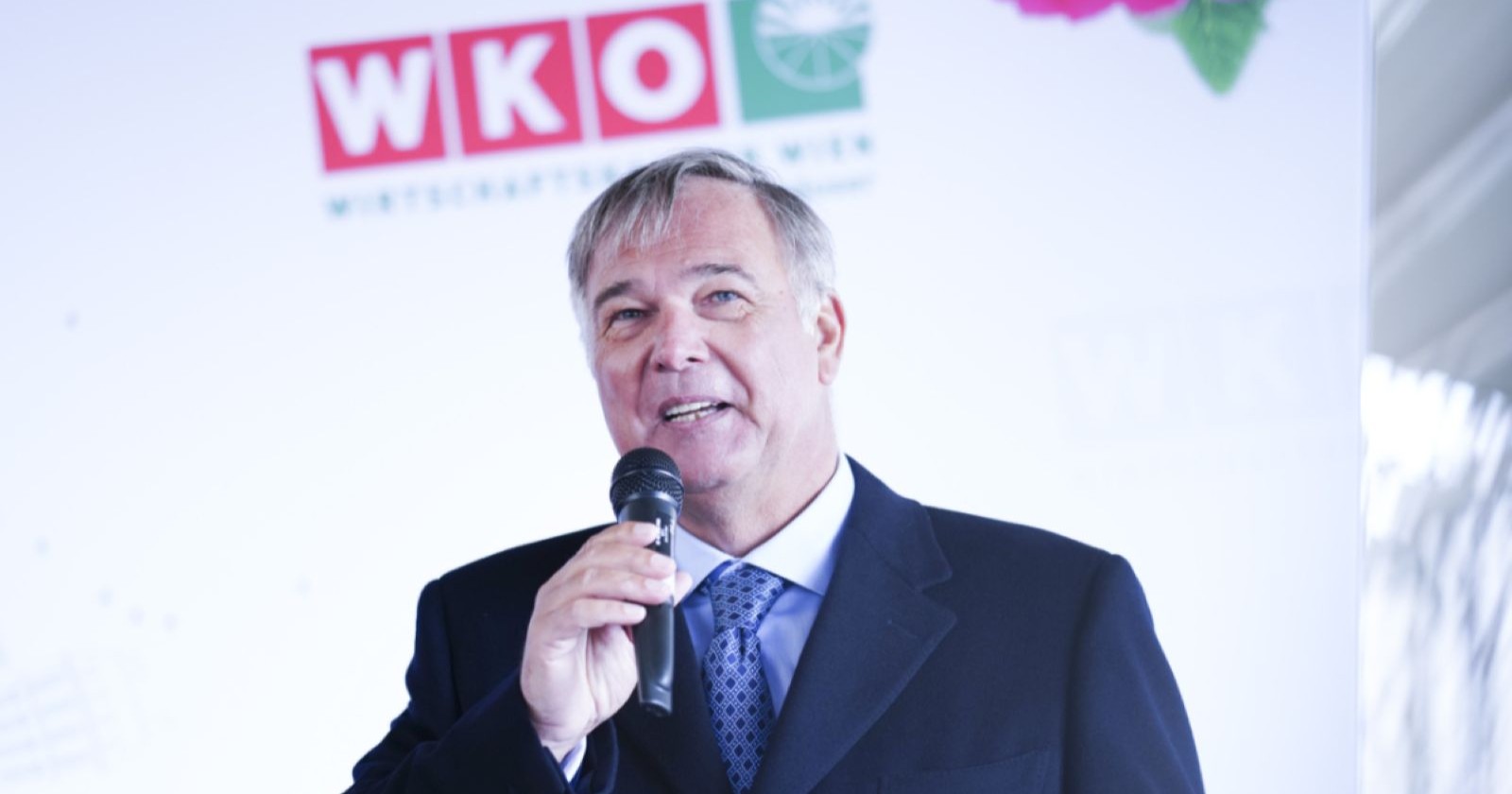 Walter Ruck bei einer Rede vor WKÖ-Logo im Hintergrund, im Fokus der aktuellen Debatte um umstrittene Aussagen und Rücktrittsforderungen