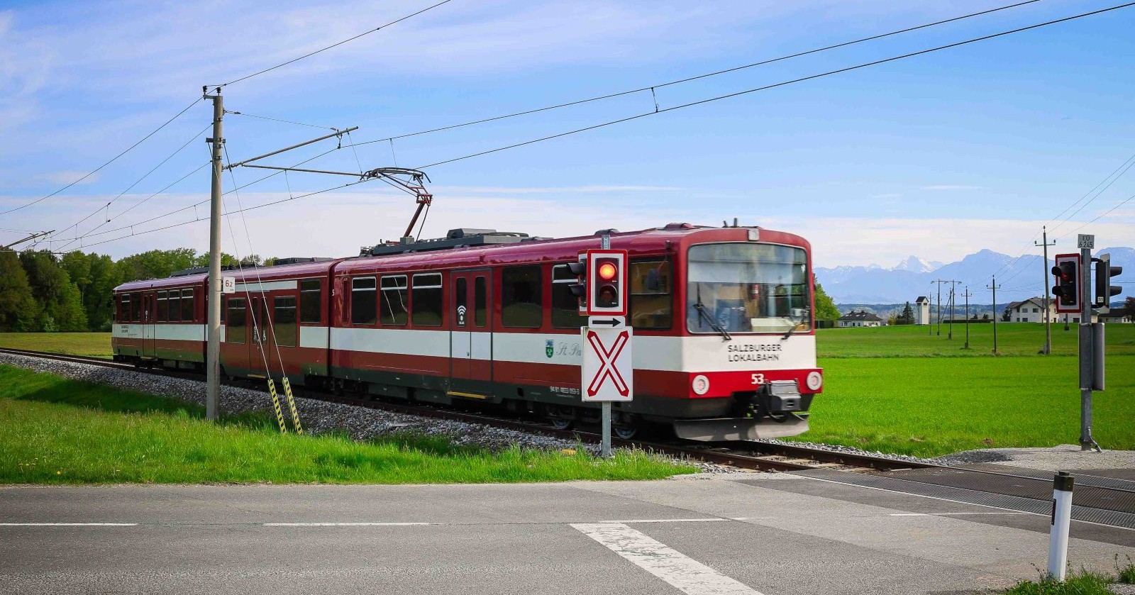 Zug fährt über einen Bahnübergang, davor steht eine Ampel