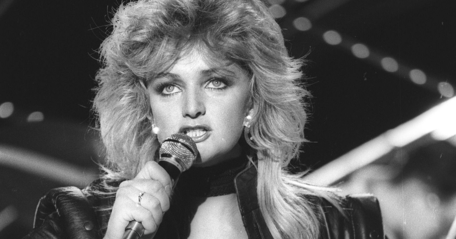 Bonnie Tyler singt auf der Bühne mit Mikrofon, schwarz-weiß Aufnahme, ikonischer Look der 1980er Jahre