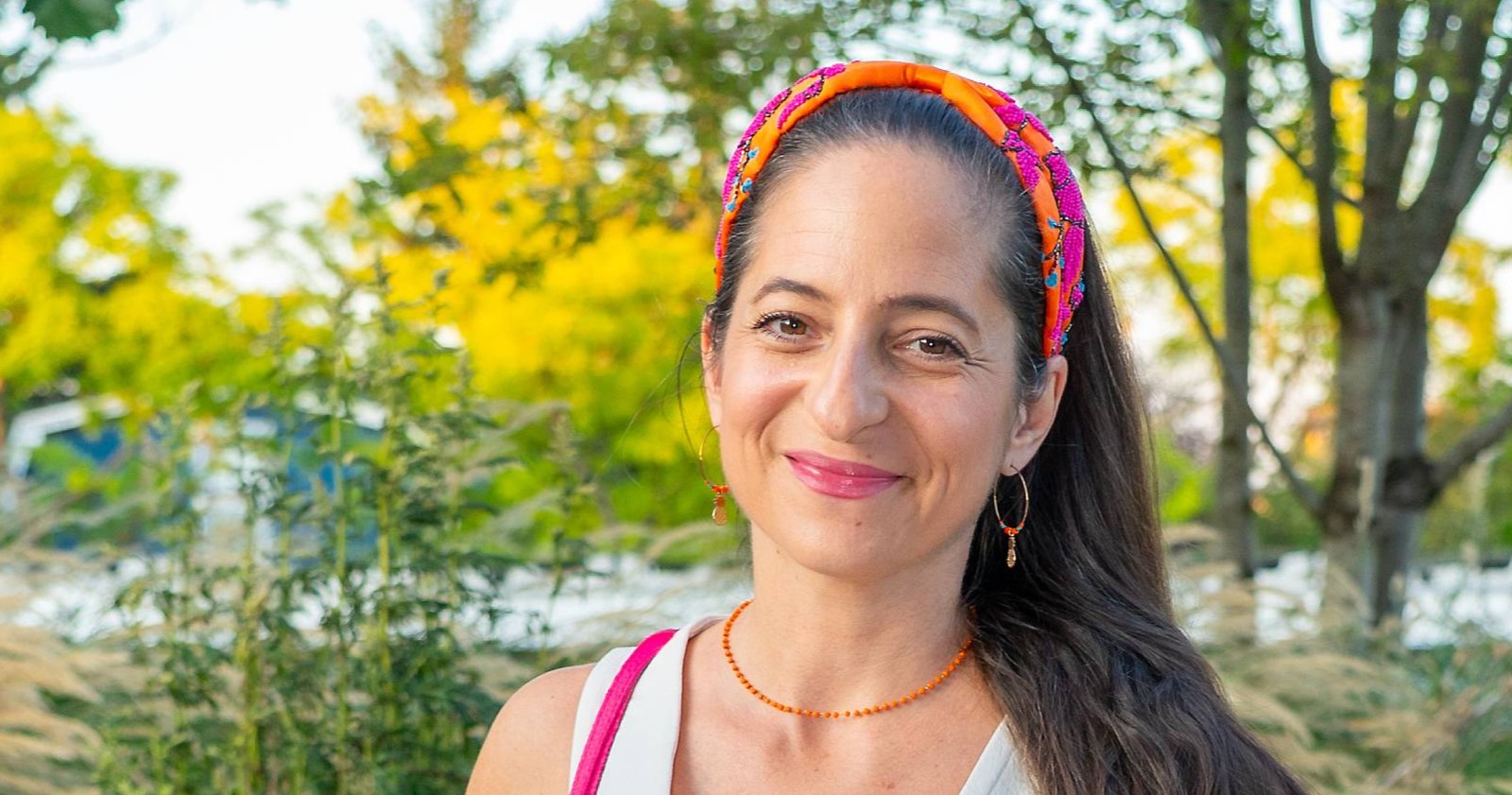 Caroline Athanasiadis lächelt im Freien mit buntem Haarband nach ihrer Operation