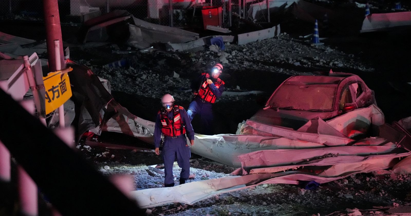 Zerstörte Gebäude und zwei Feuerwehrmänner nach dem Erdbeben in Kumamoto, Japan