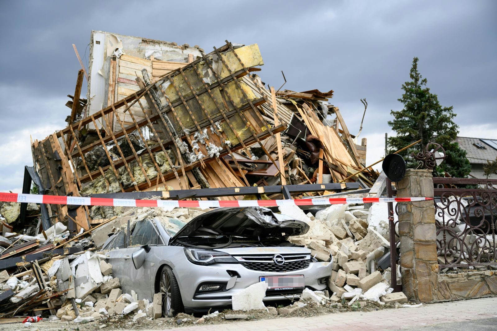 Zerstörtes Haus nach Gasexplosion in Floridsdorf mit Trümmern und beschädigtem Auto im Vordergrund