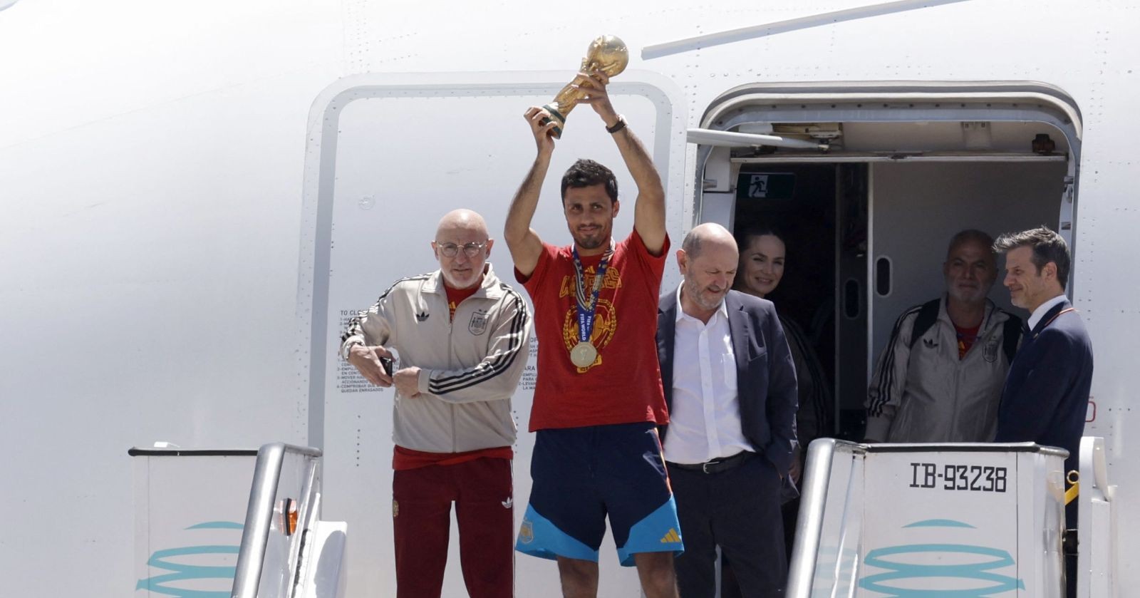 Spaniens Kapitän Rodri hält nach der Rückkehr vom Fußball-WM-Finale gegen Argentinien den WM-Pokal am Flughafen in Madrid in die Höhe.