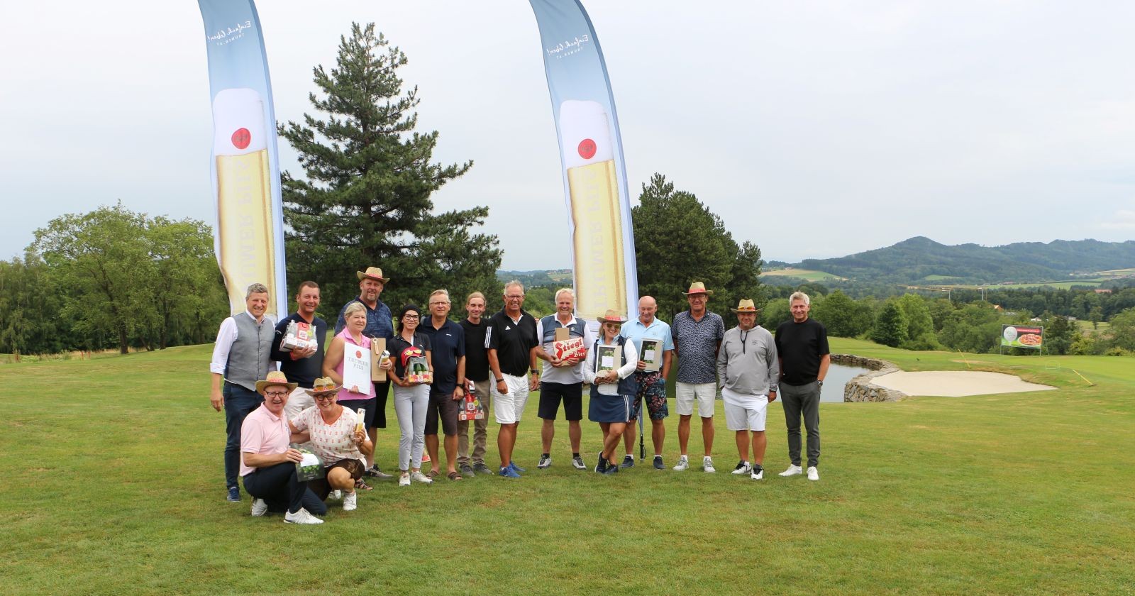 Gruppenfoto der Teilnehmerinnen und Teilnehmer eines Golfturniers mit Siegern und Organisatoren auf dem Golfplatz vor der Siegerehrung.
