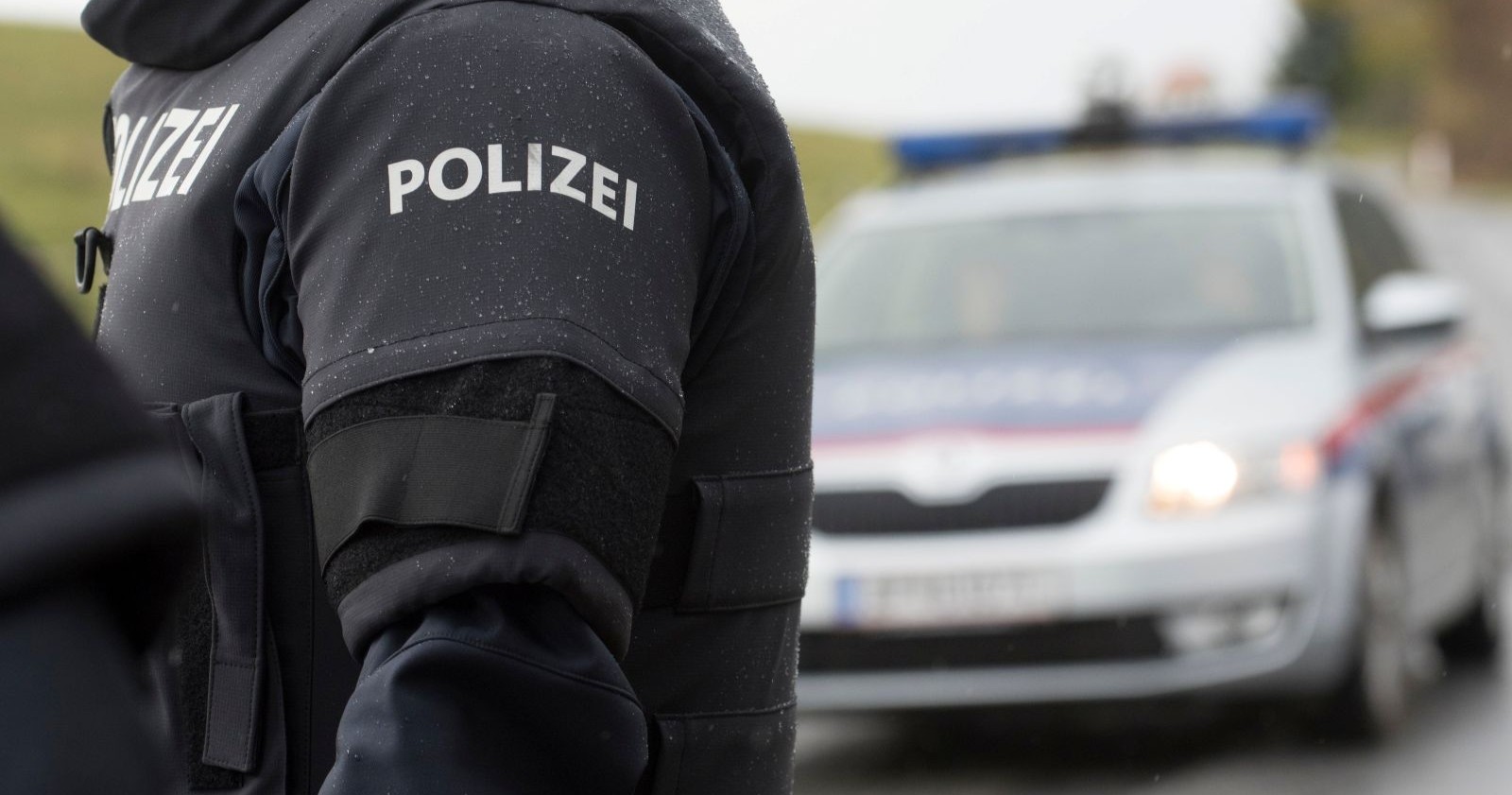 Polizist vor Einsatzfahrzeug bei Ermittlungen nach Mordversuch in Kufstein mit Gabel-Attacke
