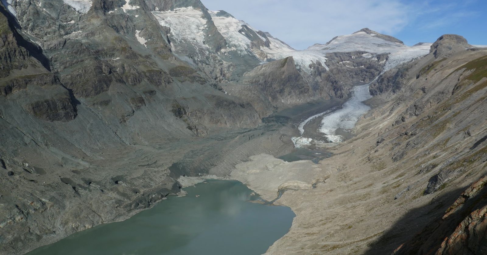 Ein schwindender Eisstrom am Fuße des Großglockners mit freiliegenden Felswänden und einem entstehenden Gletschersee