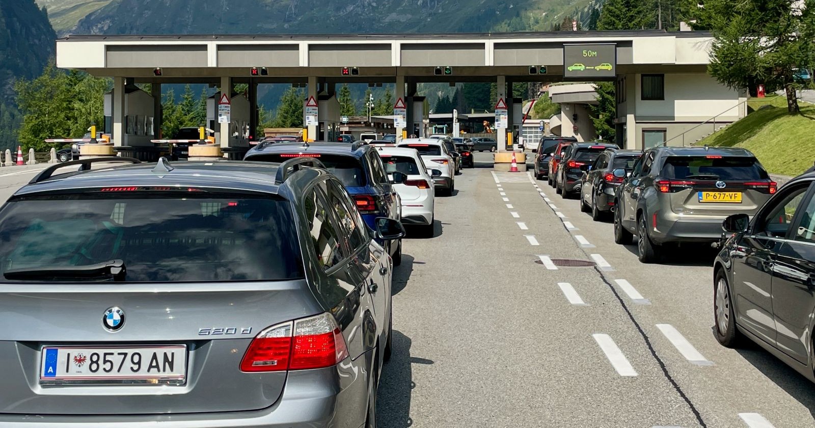 Eine lange Kolonne von Autos steht Stoßstange an Stoßstange im dichten Stau auf einer österreichischen Autobahn vor einer Bergkulisse