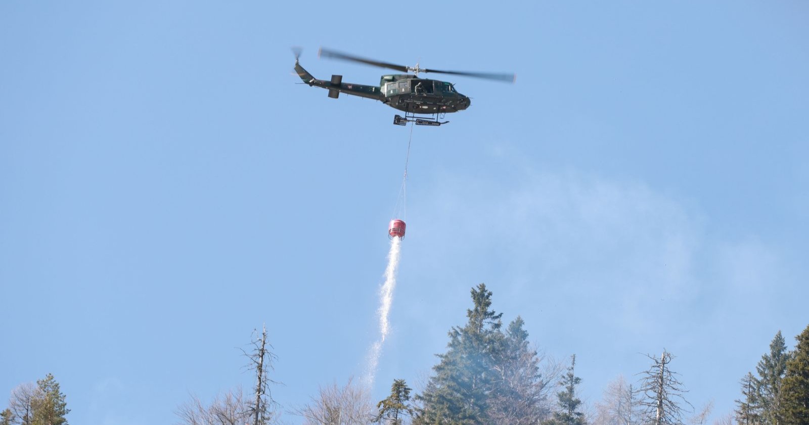 Hubschrauber löscht Waldbrand Tirol bei Wildermieming mit Löschwasser aus der Luft