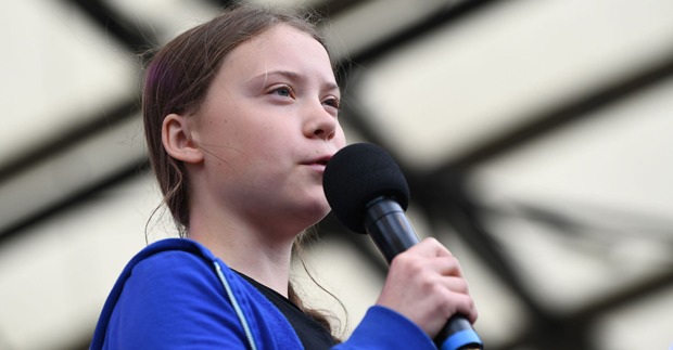 Greta Thunberg hält ein Mikrofon in der Hand und spricht.