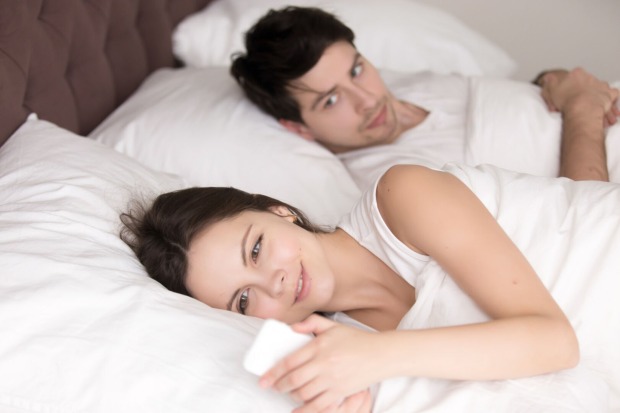 Ein Paar liegt im Bett, die Frau mit dem Rücken zum Mann, eine Nachricht von ihrem Lover lesend. Ihr Freund versucht einen Blick auf den Bildschirm zu bekommen