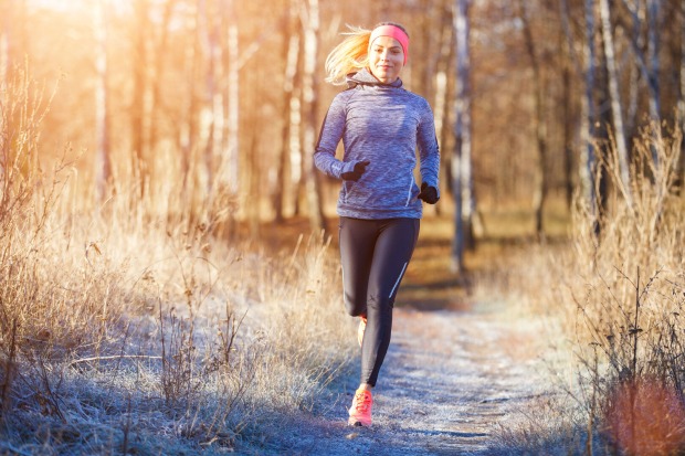 Gesund durch den Herbst: Joggerin läuft durch Herbstlandschaft