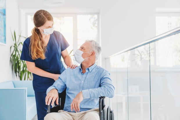 Krankenpflegerin kümmert sich um Patienten im Rollstuhl