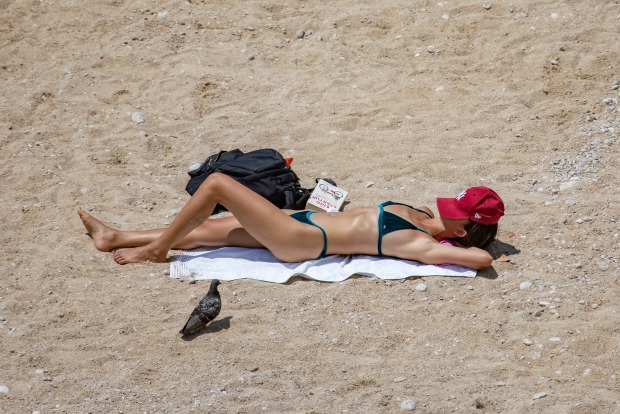 Junge Frau liegt auf einem Badetuch am Strand und sonnt sich