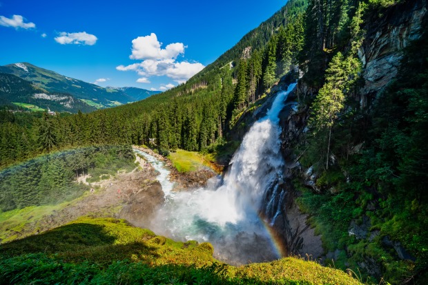 Panoramaaufnahme der mächtigen Krimmler Wasserfälle, deren Wasser einen Felsabhang hinunterstürzt