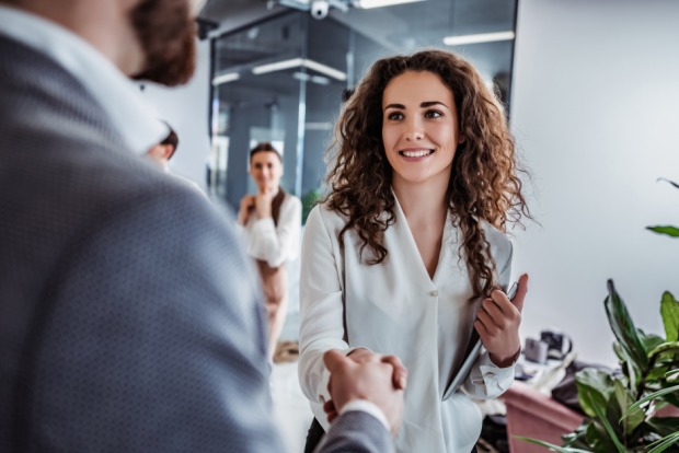 Frau begrüßt ihren Kollegen im Büro | Credit: iStock.com/Harbucks