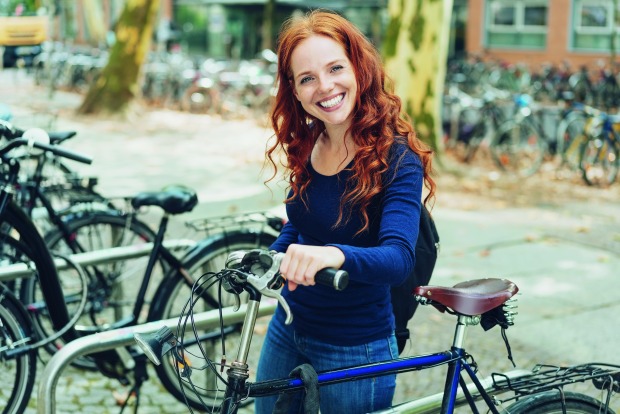 Frau lächelt in die Kamera und steht neben einem Fahrrad