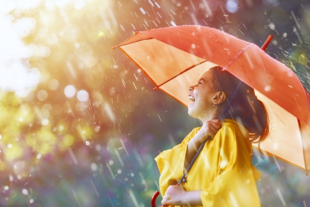Fröhliches kleines Mädchen während einem Sonnenregen unter dem Regenschirm | Credit: iStock.com/Choreograph