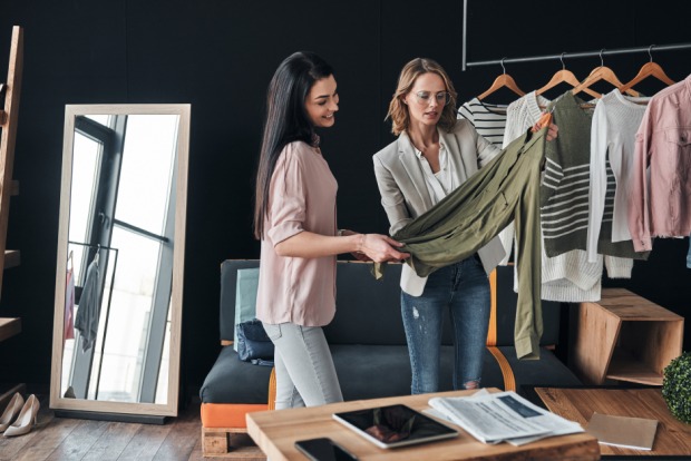 Zwei Frauen sehen gemeinsam Kleidungsstücke durch | Credit: iStock.com/g-stockstudio