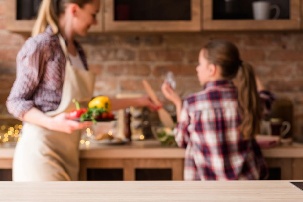 Junge Mutter verrichtet mit ihrer Tochter Hausarbeit in der Küche | Credit: iStock.com/golubovy