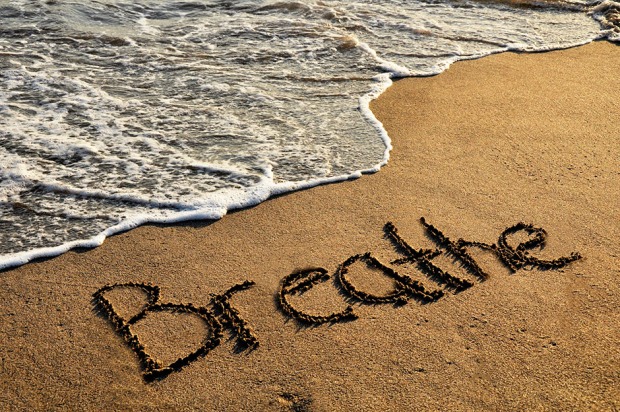 An einem Strand steht im Sand "Breathe" - englisch für "Atmen" - geschrieben | Credit: iStock.com/Circle Creative Studio