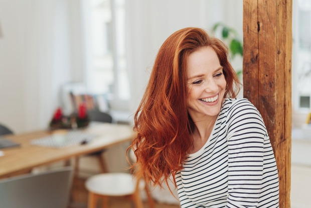 Glückliche junge Frau steht fröhlich in ihrer Küche | Credit: iStock.com/stockfour