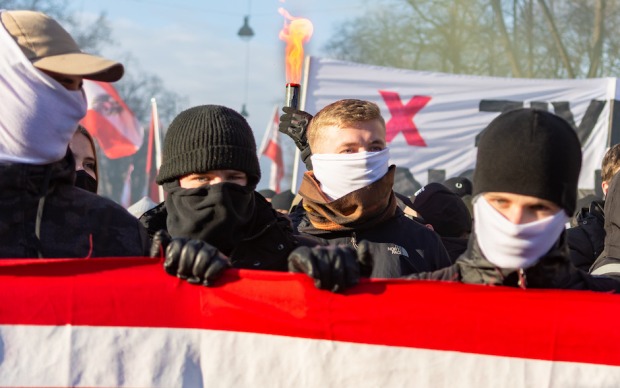 Vermummte junge Männer mit rotweißroter Fahne auf Demo