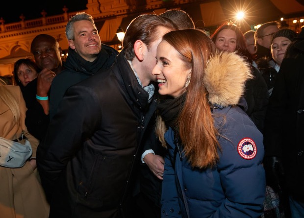 Kurz flüstert einer jungen Frau in der Daunenjacke etwas ins Ohr