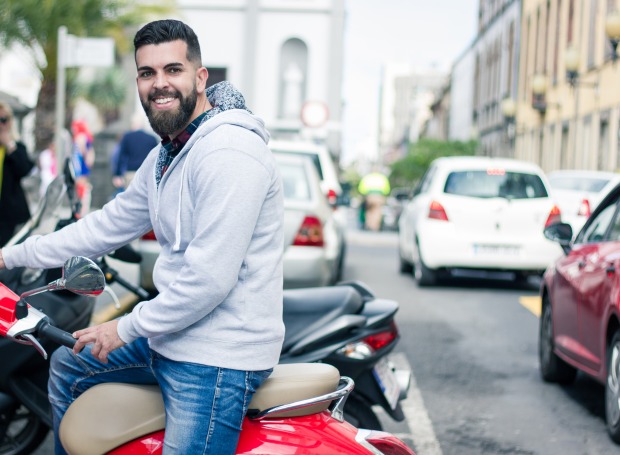 Mann steigt auf roten Motorroller auf | Credit: iStock.com/JosuOzkaritz