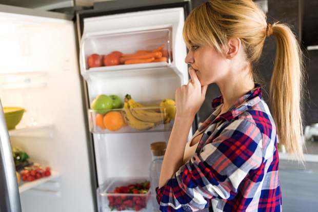 Eine junge Frau steht vor dem geöffneten Kühlschrank | Credit: iStock.com/nensuria
