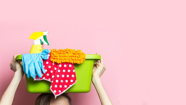 Junge Frau mit einer kleinen Wanne mit Putzmittel auf dem Kopf | Credit: iStock.com/Happycity21