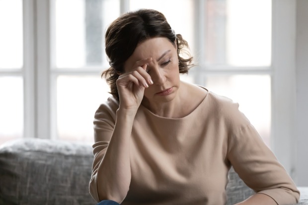 Frau greift sich an Stirn | Credit: iStock.com/fizkes