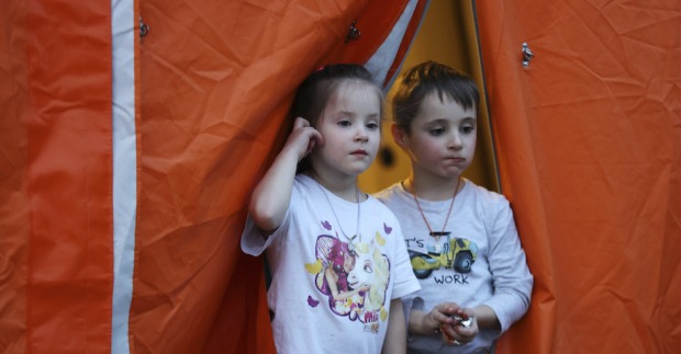 Junge und Mädchen im Kindergartenalter vor Zelteingang