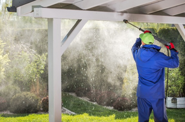 Mann reinigt mit Hochdruckreiniger Terrassendach | Credit: iStock.com/welcomia