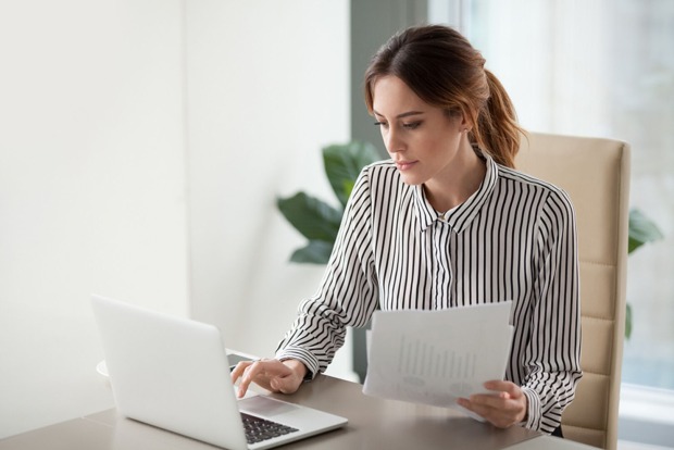 Mitarbeiterin eines Unternehmens während der Arbeit an ihrem Notebook | Credit: iStock.com/fizkes