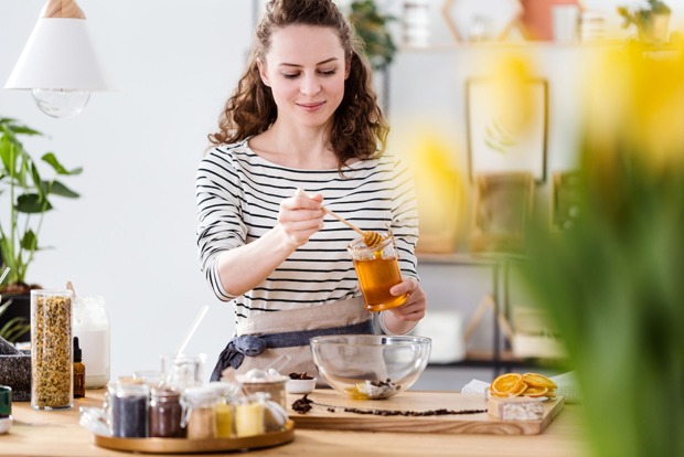 Junge Frau süßt ihr Gericht mit Honig | Credit: iStock.com/KatarzynaBialasiewicz