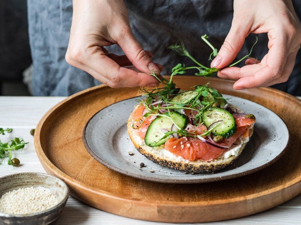 Frau richtet sich ein Lachsbrötchen | Credit: iStock.com/Olga Peshkova