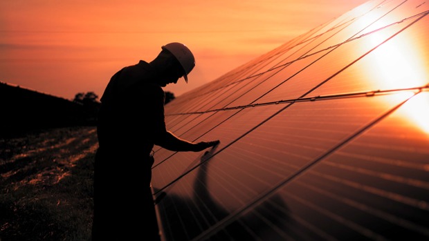 Bei Sonnenaufgang überprüft ein Monteur Solarmodule auf dem Dach eines Hauses | Credit: iStock.com/Felbaba Volodymyr
