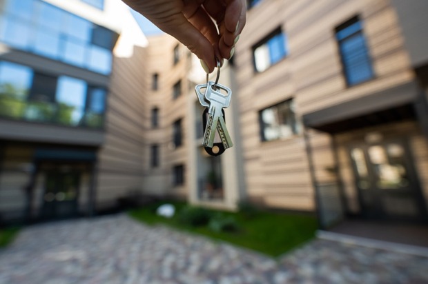 Frau hält Haustürschlüssel in die Luft | Credit: iStock.com/inside-studio
