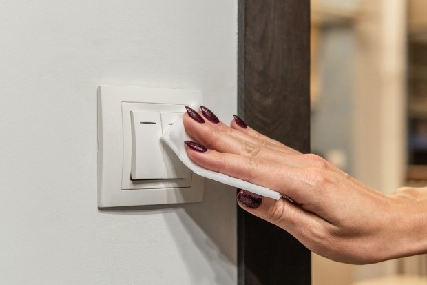Frau säubert Lichtschalter| Credit: iStock.com/Medvedkov