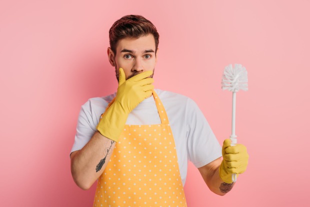 junger Mann mit gelber Schürze und Klobürste | Credit: iStock.com/LightFieldStudios