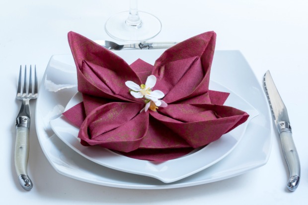 Eine aus Papierservietten gefaltete Artischocke als Dekoration auf einem Essteller | Credit: iStock.com/guy-ozenne