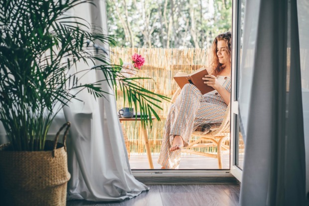 Frau sitzt am Balkon und liest | Credit: iStock.com/Maria Korneeva