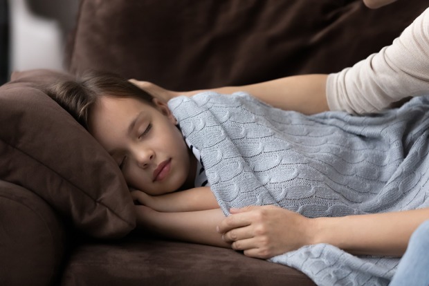 Mutter deckt ihre schlafende Tochter zu | Credit: iStock.com/fizkes