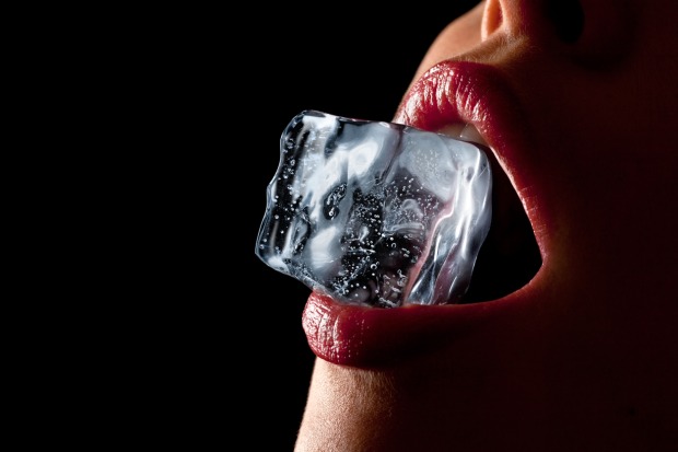 Eine Frau hat einen Eiswürfel zwischen ihren Lippen
