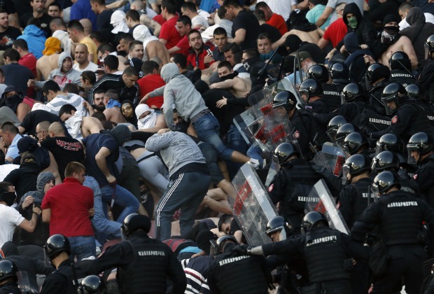 Bereitschaftspolizei, die gegen Tumulte auf einer Fußballtribüne vorgeht.